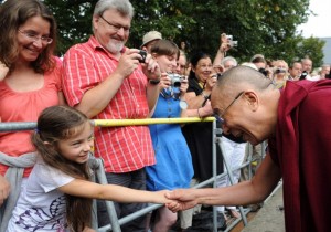 Tibetan spiritual leader the Dalai Lama shakes hands with a young girl during visit to monastery in Seligenstadt