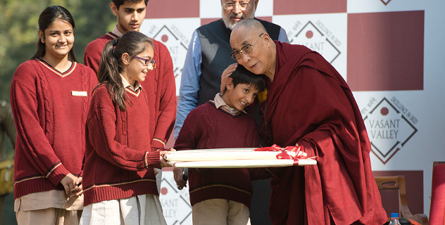 His Holiness the Dalai Lama embracing a young student as they offer him a memento of his visit to Vasant Valley School in New Delhi, India on December 6, 2013. Photo/Tenzin Choejor/OHHDL