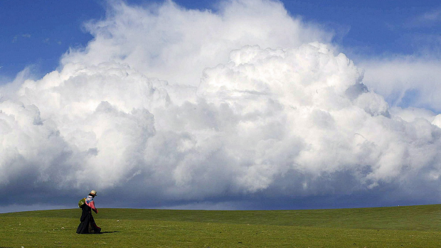 A Tibetan woman makes her way across the across grasslands on the Tibetan Plateau. Photo: AFP