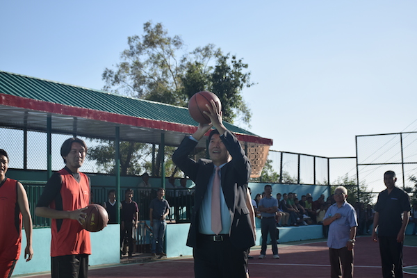 Sikyong with a basket ball, throwing a shot at the hoop.