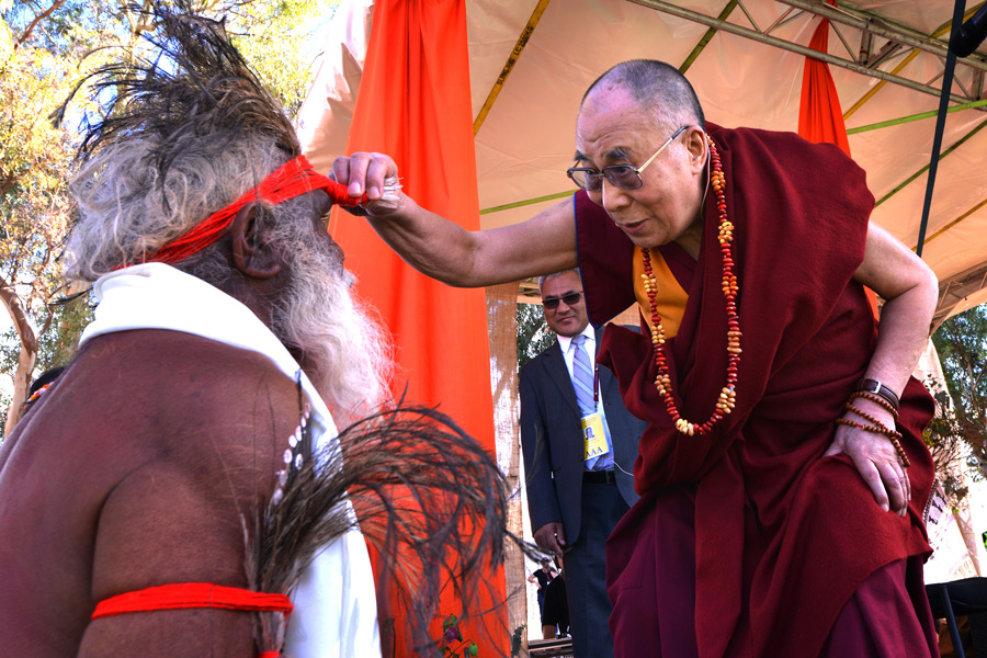His Holiness the Dalai Lama tells one of the masked dancers who welcomed him, �I want to see your nose!� prior to his talk at the Yulara Oval in Uluru, Northern Territory, Australia on June 13, 2015. Photo/Rusty Stewart