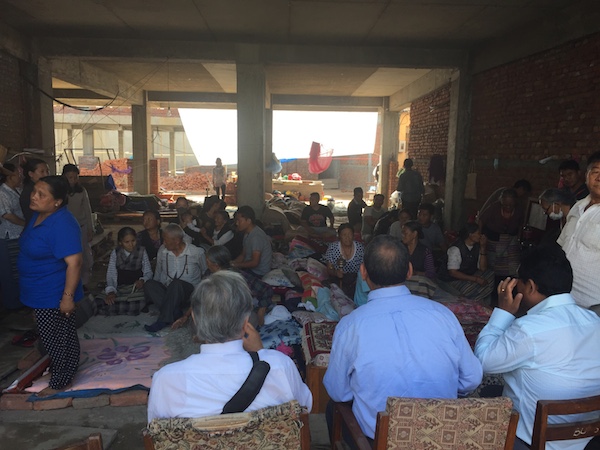 Kalon Ngodup Tsering with Tibetans temporarily displaced by the earthquake. they were sheltering at an under-contsruction building.
