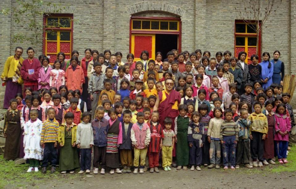 In this photo taken June 1999 and released by Tsering Woeser on July 13, 2015, Tenzin Delek Rinpoche, center in red robes, poses for photo with orphans at a school in Nyagqu County, (Tsering Woeser via AP)