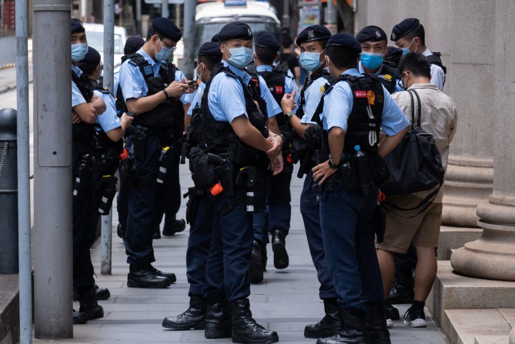 Police officers stop and search a man in the vicinity of a planned lunchtime protest in Hong Kong on Aug. 10. (Roy Liu/Bloomberg News)