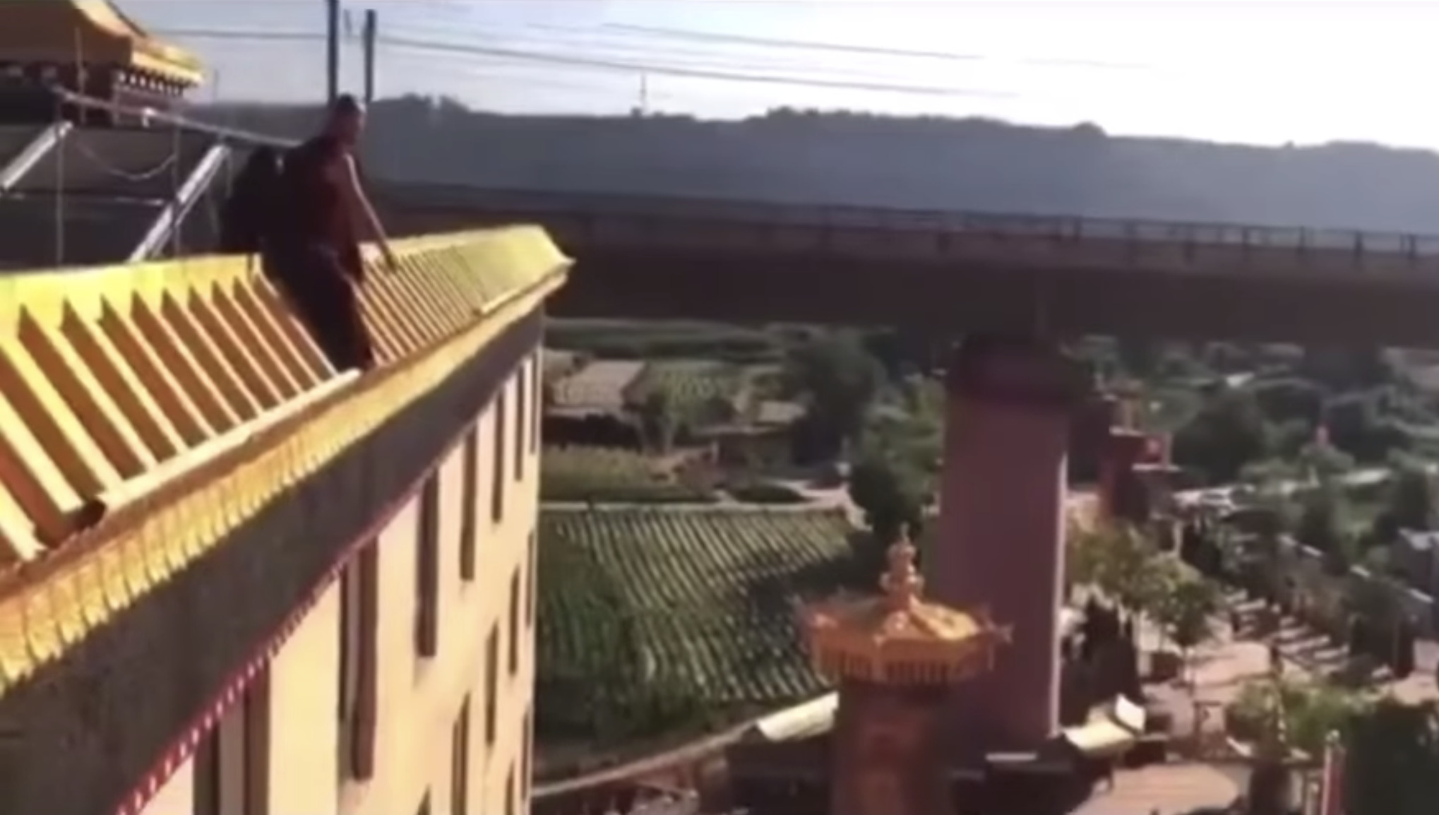 A monk trying to jump from the rooftop in protest against the Chinese authorities' forced eviction. 